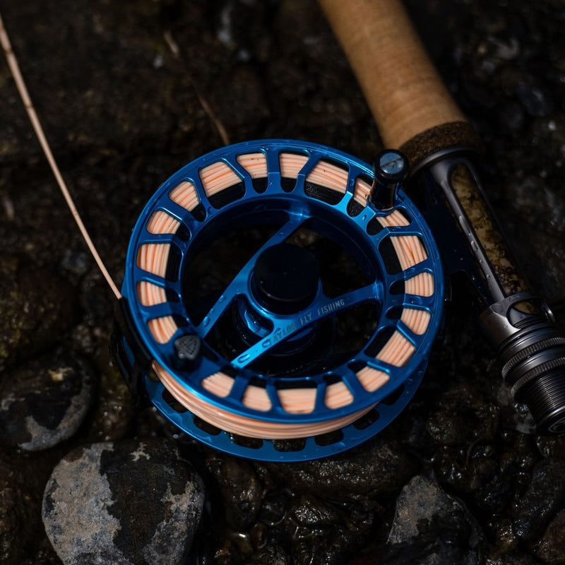 Close-up of a 444 peach line on a blue fishing reel on a dark, natural background