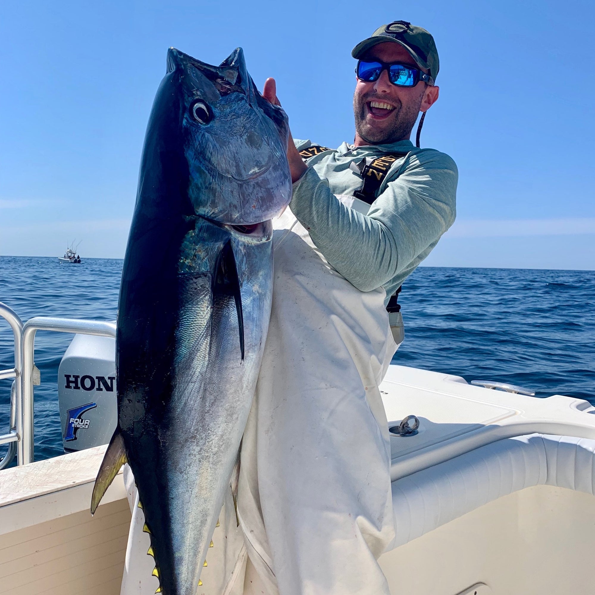 A man is standing on a boat and holding up a large fish. 